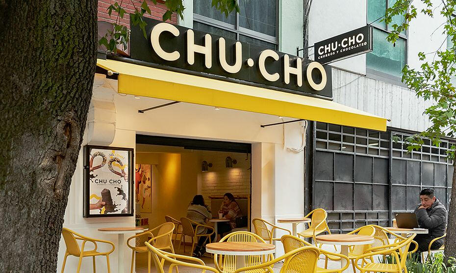 A Chu Cho churros and chocolate shop with a yellow awning and yellow patio chairs